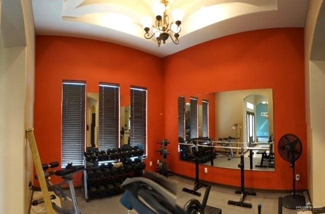 gym with vaulted ceiling and a notable chandelier