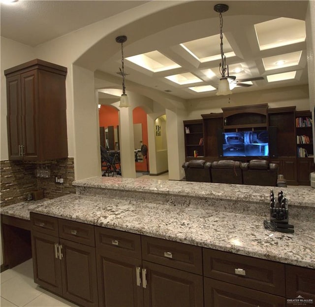 kitchen featuring pendant lighting, backsplash, coffered ceiling, ceiling fan, and light stone counters