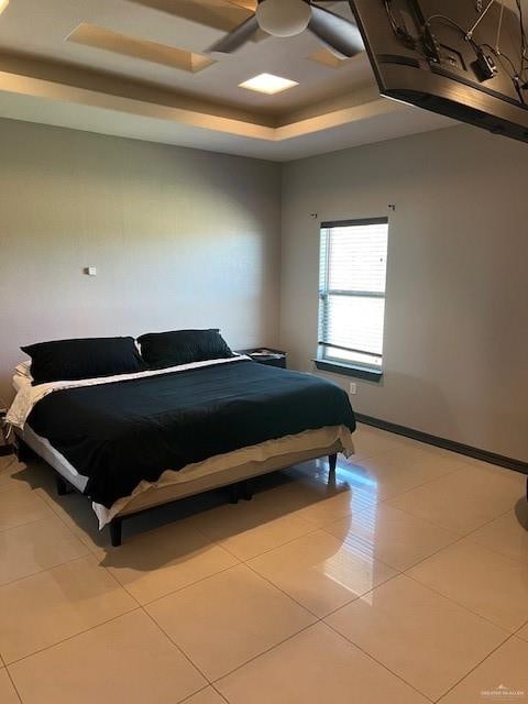 tiled bedroom with a raised ceiling and ceiling fan