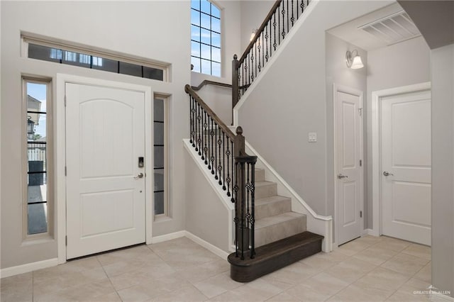 entryway with light tile patterned flooring, a high ceiling, and a wealth of natural light