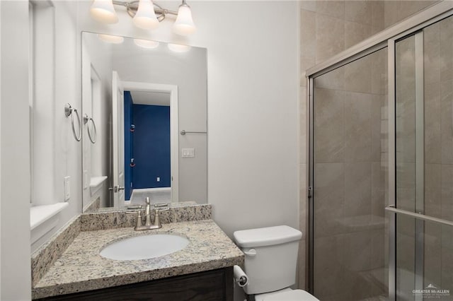 bathroom featuring vanity, toilet, and a shower with shower door