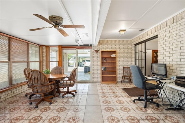 tiled home office with ceiling fan and brick wall