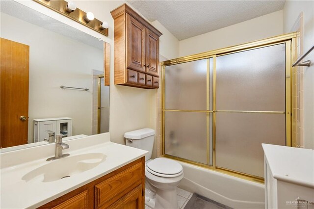 full bathroom with tile patterned floors, a textured ceiling, toilet, shower / bath combination with glass door, and vanity