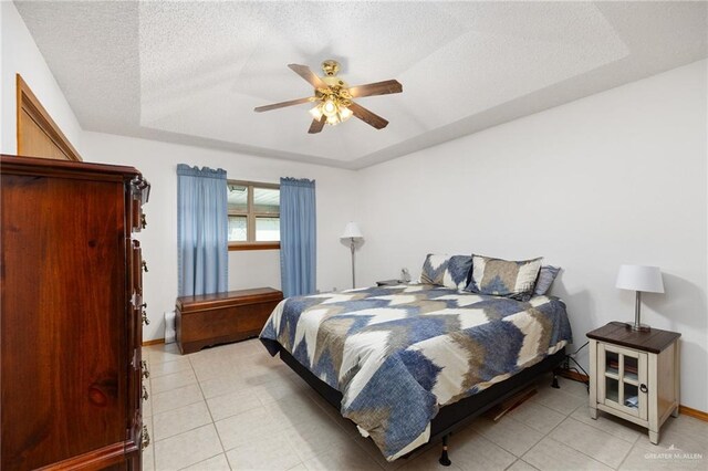 tiled bedroom featuring a raised ceiling, ceiling fan, and a textured ceiling