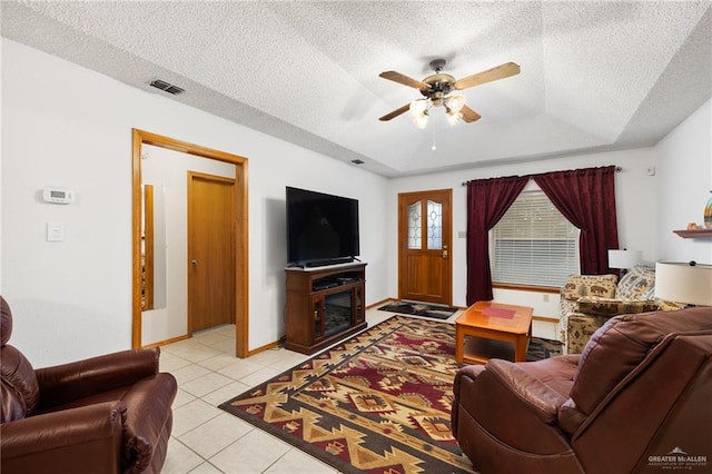 tiled living room with ceiling fan, a fireplace, a textured ceiling, and a tray ceiling