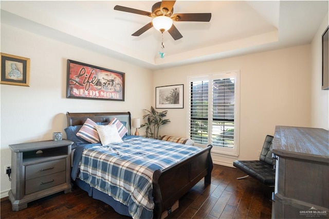 bedroom with a raised ceiling, ceiling fan, and dark hardwood / wood-style flooring