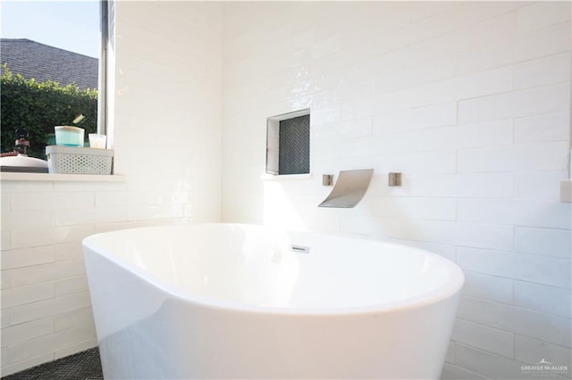 bathroom with a bathing tub and tile walls