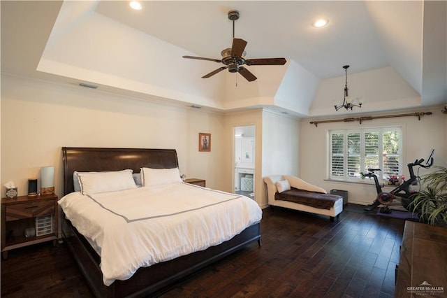 bedroom featuring ceiling fan with notable chandelier, connected bathroom, dark hardwood / wood-style floors, and a raised ceiling