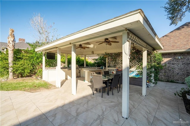 view of patio featuring a gazebo, ceiling fan, an outdoor bar, and an outdoor kitchen