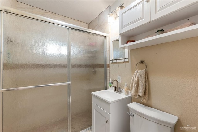 bathroom with vanity, a shower with shower door, and toilet