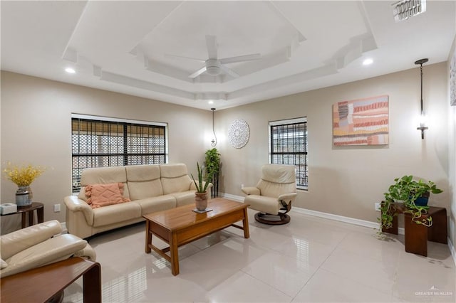 living room featuring a raised ceiling, light tile patterned flooring, and ceiling fan