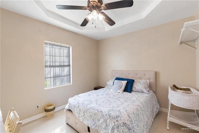 carpeted bedroom featuring ceiling fan and a tray ceiling