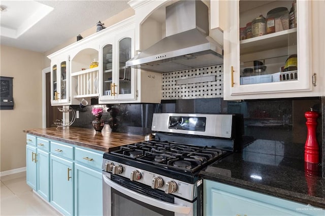 kitchen featuring wall chimney range hood, blue cabinetry, white cabinetry, tasteful backsplash, and gas stove