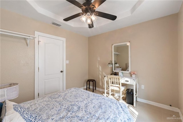 tiled bedroom with a raised ceiling and ceiling fan