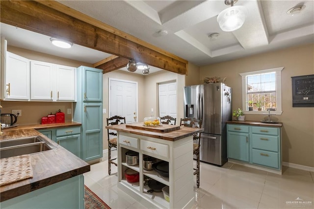 kitchen featuring white cabinetry, sink, stainless steel fridge, and butcher block countertops