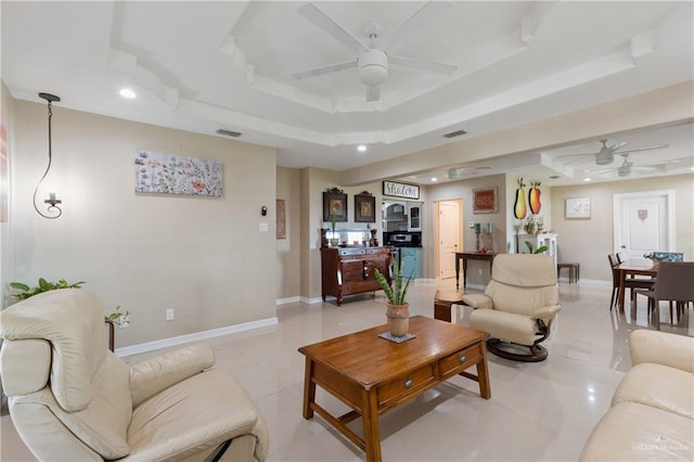 living room with light tile patterned floors, a raised ceiling, and ceiling fan