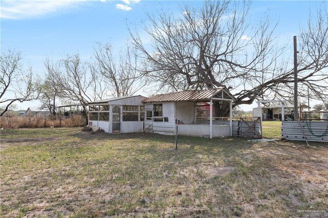 back of property featuring a sunroom and a lawn