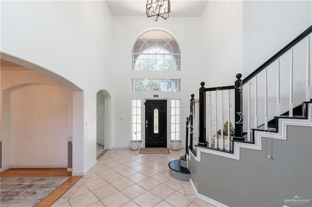 foyer entrance featuring a towering ceiling, light tile patterned floors, and a notable chandelier