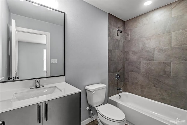 full bathroom featuring vanity, tiled shower / bath combo, and toilet