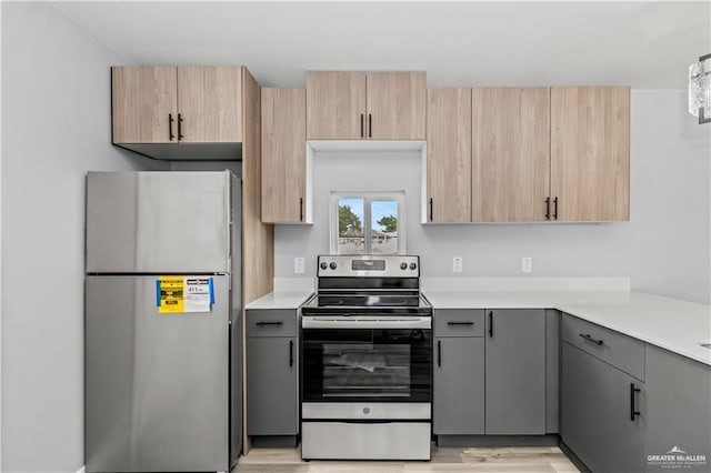 kitchen featuring gray cabinets, light brown cabinetry, stainless steel appliances, and light hardwood / wood-style floors