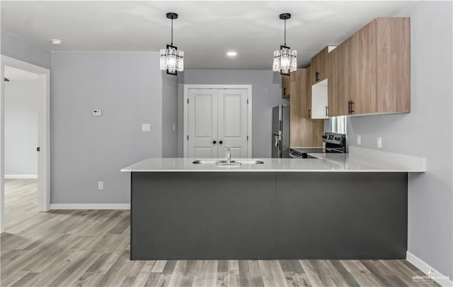 kitchen with kitchen peninsula, appliances with stainless steel finishes, hanging light fixtures, and sink