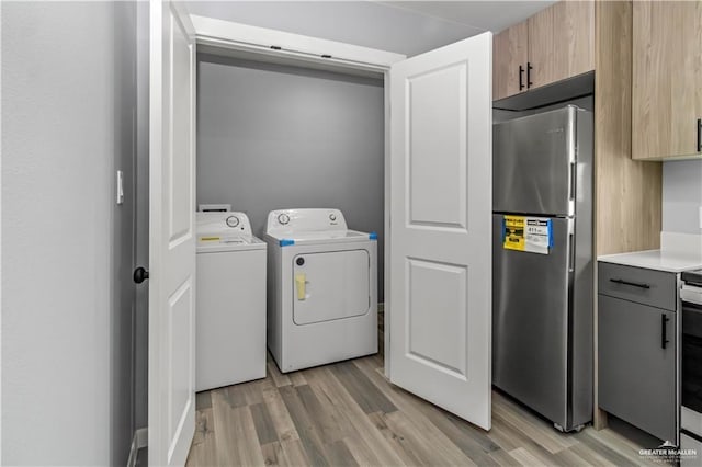 laundry area featuring washing machine and dryer and light wood-type flooring