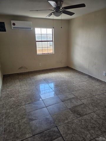 spare room with ceiling fan and a wall mounted air conditioner