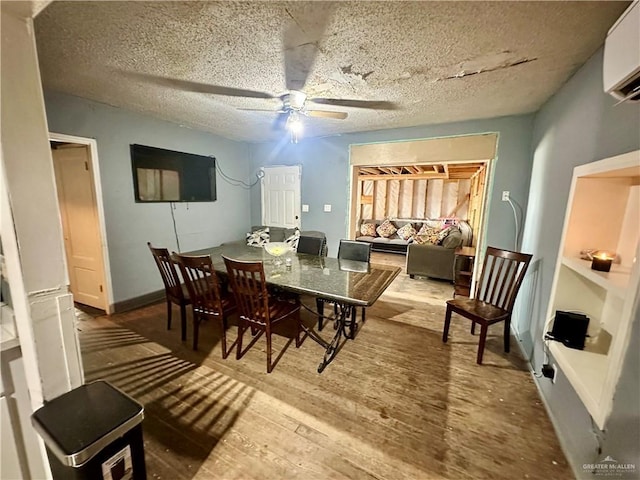 dining area featuring a ceiling fan, a textured ceiling, wood finished floors, a wall mounted air conditioner, and baseboards