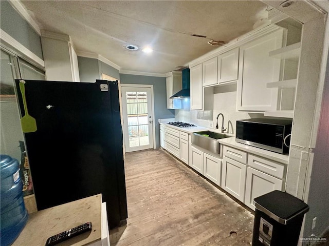 kitchen featuring wall chimney exhaust hood, ornamental molding, freestanding refrigerator, open shelves, and a sink