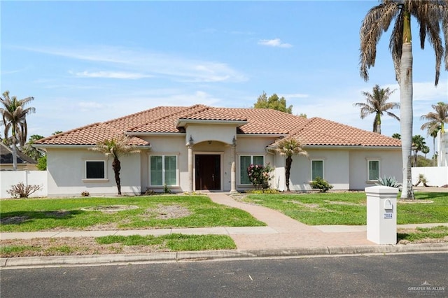 mediterranean / spanish house with stucco siding, a tiled roof, a front yard, and fence