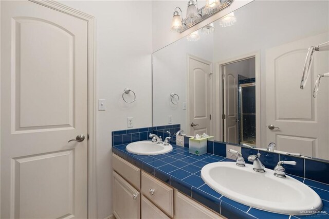 bathroom featuring double vanity, a shower with door, and a sink