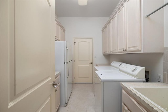 laundry area featuring light tile patterned flooring, cabinet space, washer and dryer, and a sink