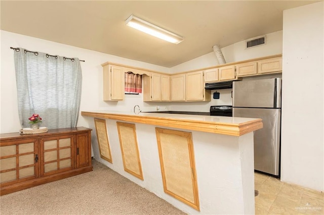 kitchen featuring electric range, visible vents, freestanding refrigerator, a peninsula, and vaulted ceiling