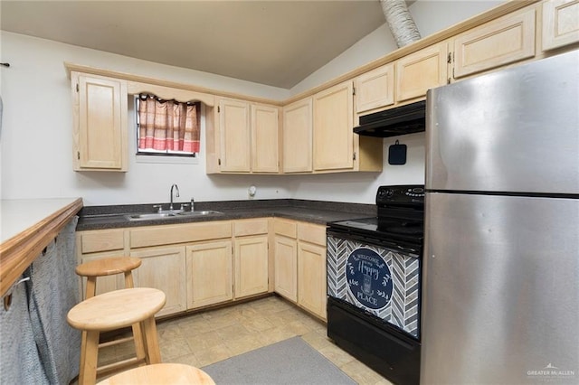 kitchen with under cabinet range hood, light brown cabinets, a sink, and freestanding refrigerator