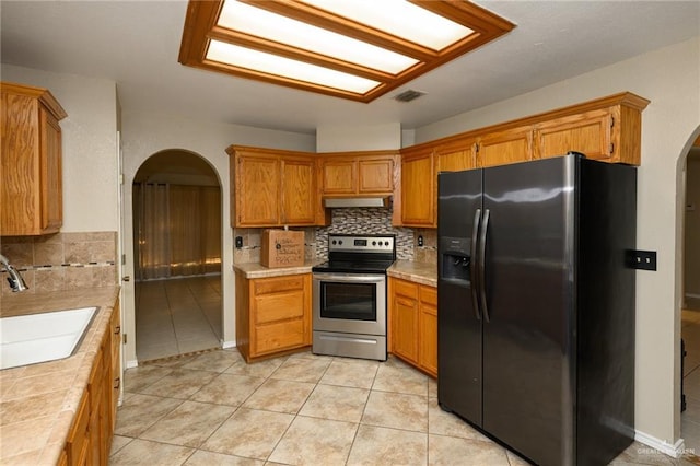 1905 N 8th St, Harlingen, TX 78550 - kitchen with refrigerator with ice dispenser, stainless steel electric stove, arched walkways, a sink, and under cabinet range hood