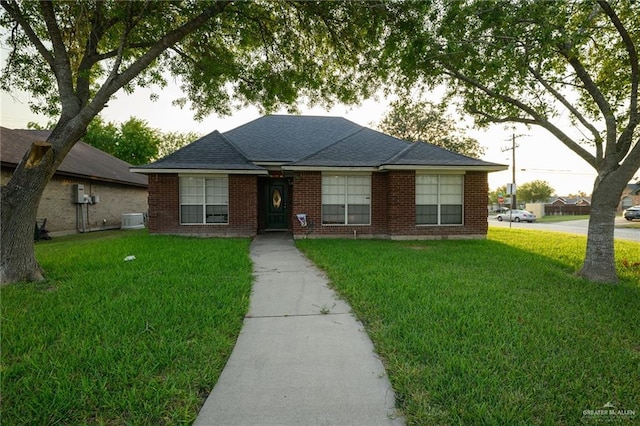 1905 N 8th St, Harlingen, TX 78550 - bungalow featuring a front lawn, central air condition unit, brick siding, and roof with shingles