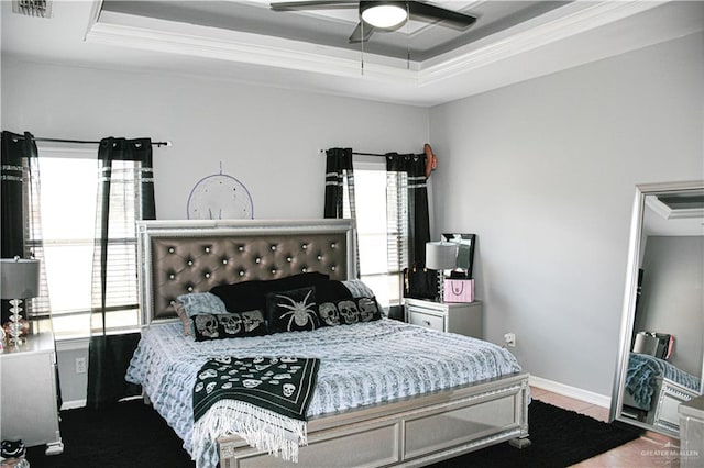 bedroom with hardwood / wood-style floors, a tray ceiling, ceiling fan, and crown molding