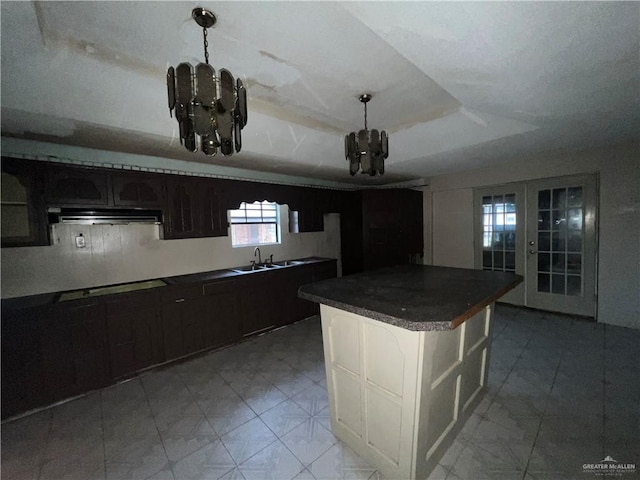 kitchen with french doors, cooktop, dark brown cabinetry, a tray ceiling, and sink