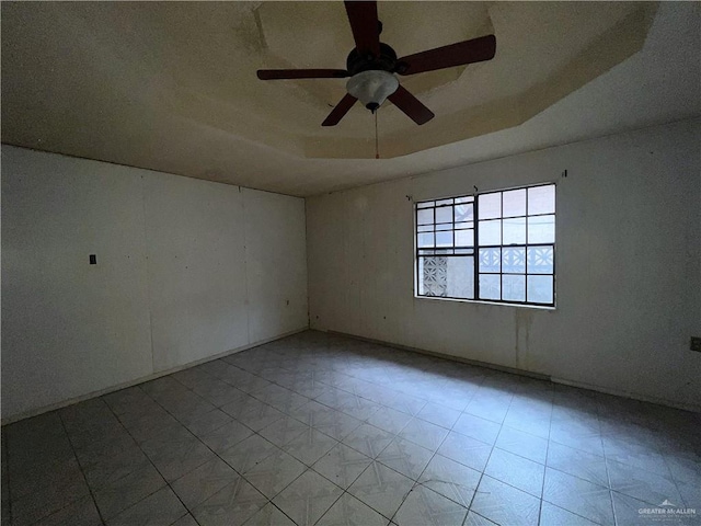 spare room with ceiling fan and a raised ceiling