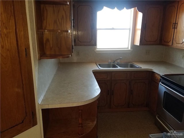 kitchen featuring brown cabinetry, stainless steel range with electric cooktop, light countertops, and a sink