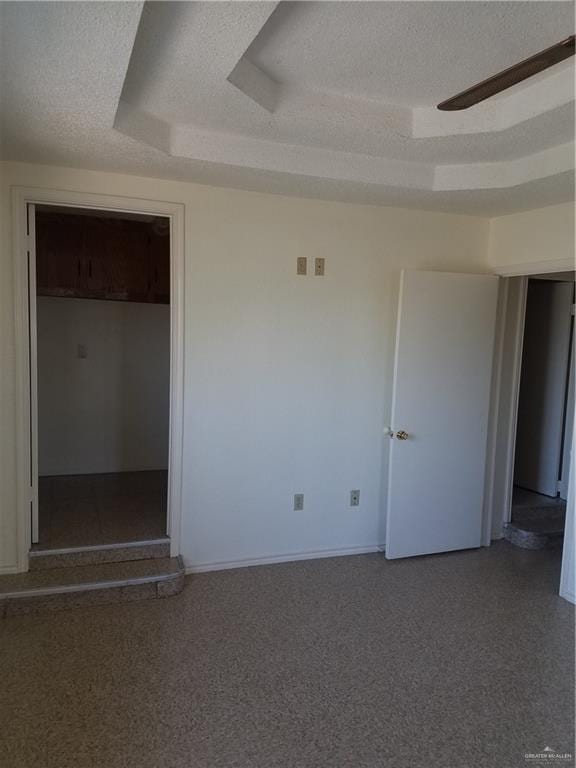 spare room with ceiling fan, baseboards, a raised ceiling, and a textured ceiling