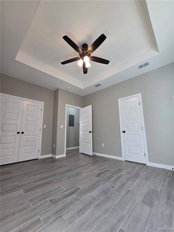 1204 Cornerstone Loop, Rio Grande City, TX 78582 - unfurnished bedroom with a tray ceiling, wood finish floors, baseboards, and visible vents