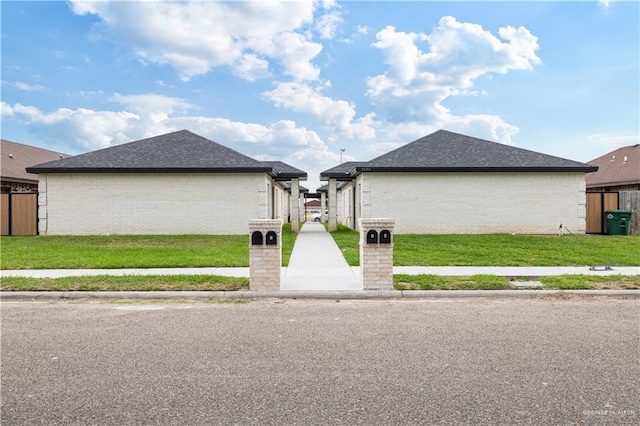 1204 Cornerstone Loop, Rio Grande City, TX 78582 - view of property exterior with a yard, roof with shingles, brick siding, and fence