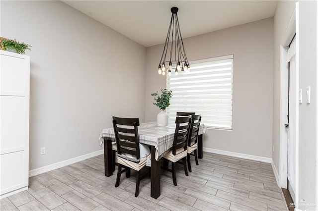 dining space with an inviting chandelier, baseboards, and wood finish floors