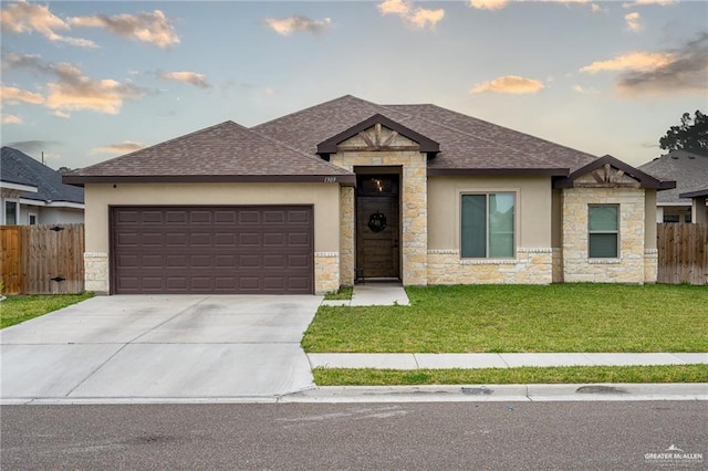 view of front facade with a yard, an attached garage, driveway, and fence