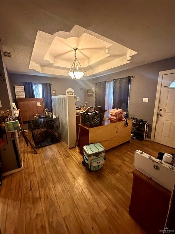 bedroom with hardwood / wood-style floors and a tray ceiling