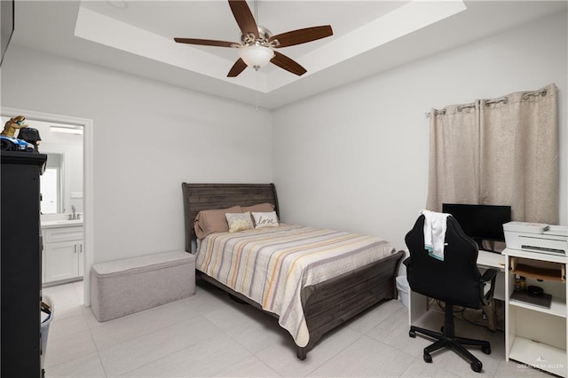 tiled bedroom featuring ceiling fan, ensuite bath, sink, and a tray ceiling