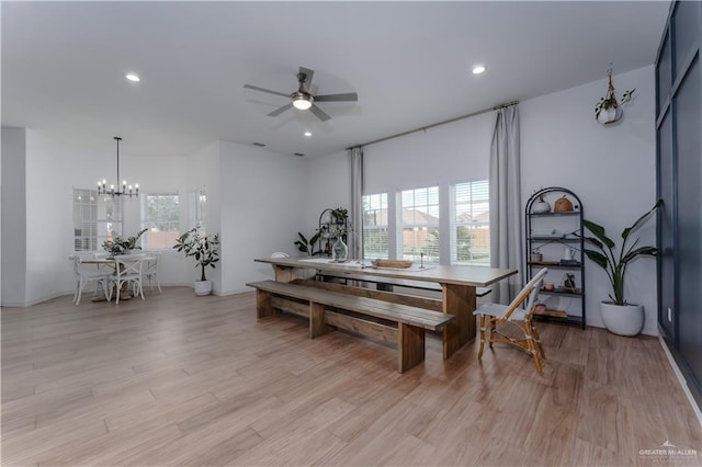 dining area featuring light hardwood / wood-style flooring, ceiling fan with notable chandelier, and plenty of natural light