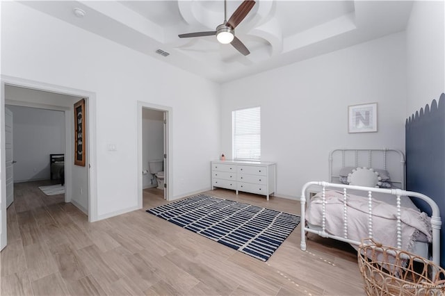 bedroom with a raised ceiling, ceiling fan, and light hardwood / wood-style floors