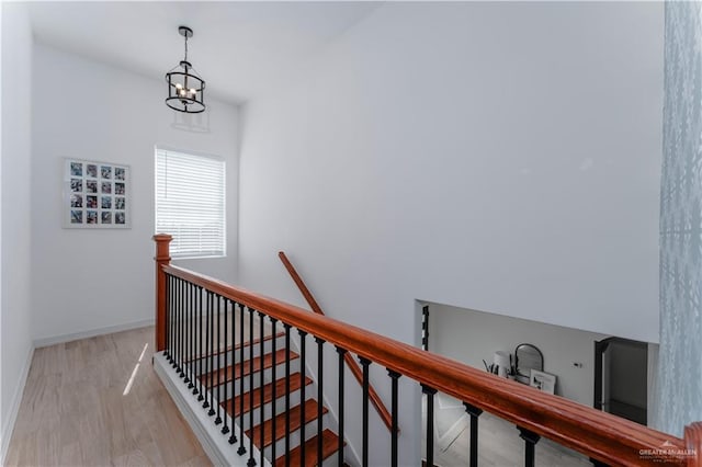 stairway with wood-type flooring and a chandelier